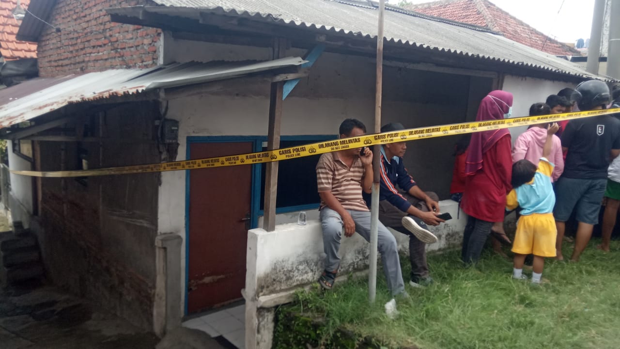 Polisi memasang Police line di TKP rumah korban yang dikerumuni warga di Desa Bambe RT1 RW 1, Kecamatan Driyorejo, Rabu (24/11/2021)./ Foto: Bram